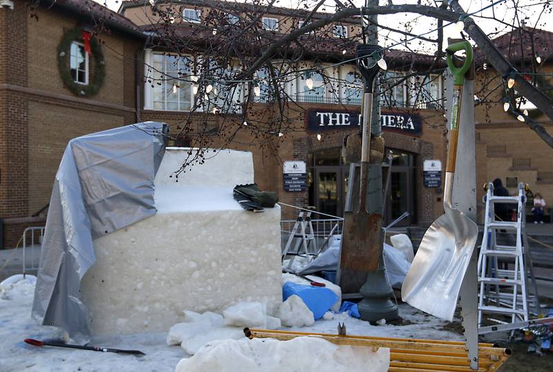 Snow carving tools hang from a tree in front of a covered block of snow to protect the snow from rain and heat on Thursday., Jan. 30, 2025, Snow carvers have started carving their 15 massive snow sculptures for America’s Snow Sculpting Invitational during Winterfest in Lake Geneva. Winterfest, runs through Feb, 2, 2025. The warm and rainy weather has slowed down the carving of the snow.