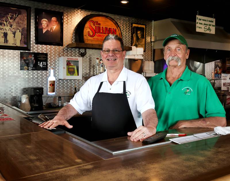 Earl (left) and Greg Sullivan, who own Sullivan's Tavern with brother Albert and sister-in-law Cindy, (not pictured) stand behind the bar Thursday, May 15, 2025, at the tavern in DeKalb. The bar is celebrating 80 years in business with an event Saturday, May 17, that will include food and live entertainment.