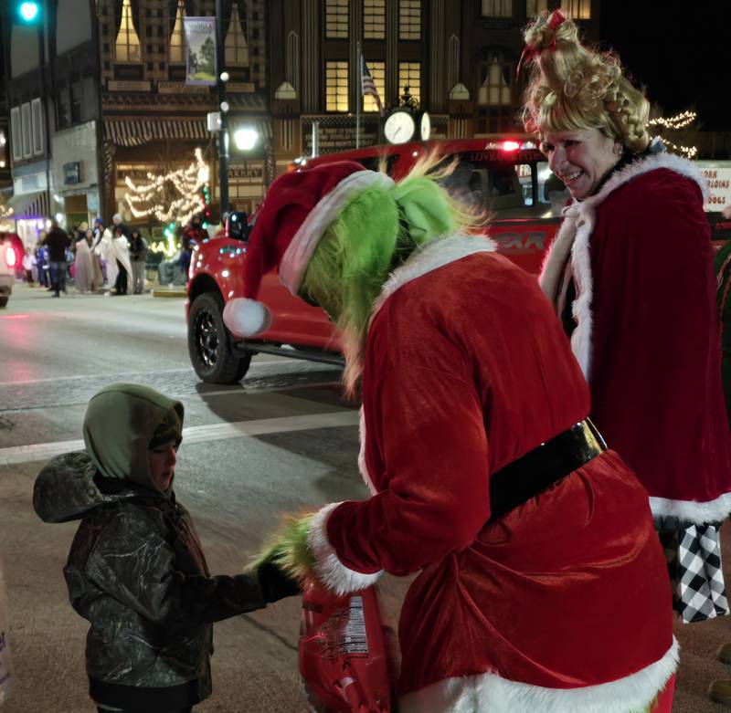 The Grinch greets a child Saturday, Nov. 30, during the Lighted Christmas Parade in downtown Streator.