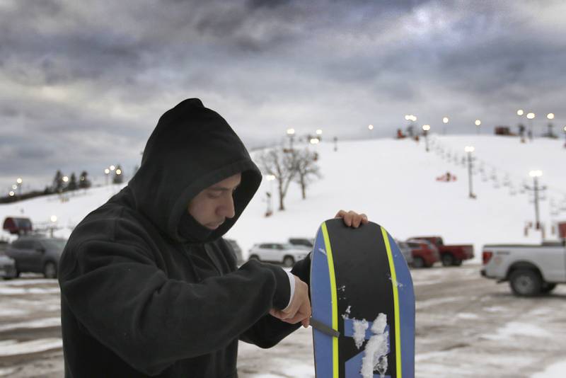 Pablo Nabarro prepares his snowboard before heading down the hill at Wilmot Mountain Ski Resort on Thursday, Jan. 16, 2025, in Wilmot, Wisconsin.