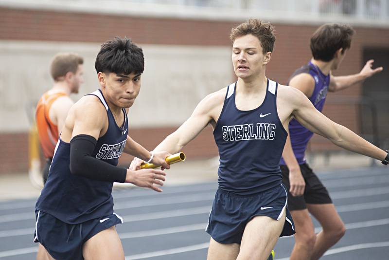 Sterling's John Cid takes the baton from teammate Dale Johnson in the 4x200 Friday, April 29, 2022 at the Sterling Night Relays.