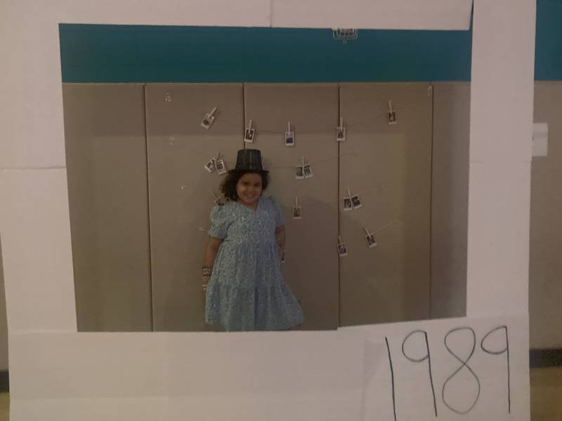 Raffle winner 10-year-old Jaliah Lombardo poses in the "1989" polaroid photo prop with her prize hat.
