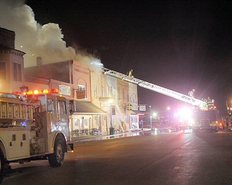 Firefighters battle flames above apartment outside Skoogs Pub & Grill on Sunday, May 10, 2015 downtown Utica.