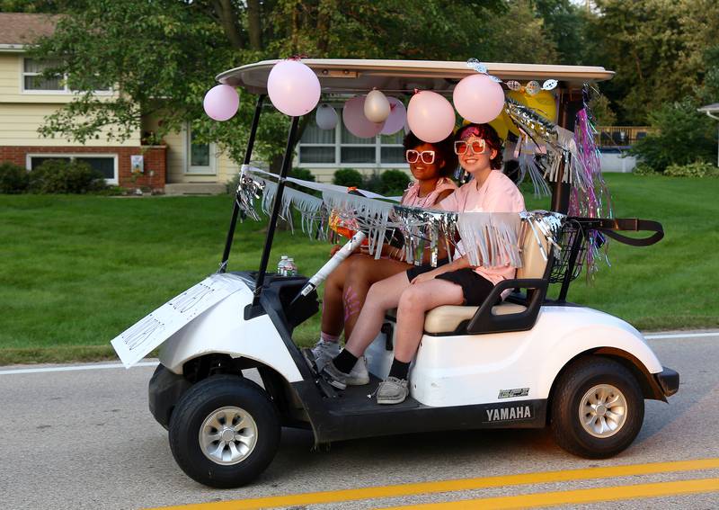 Seniors Avery Ackerman and Megan Johnson drive a golf cart in the Kaneland Homecoming Parade in Kaneville on Wednesday, Sept. 14, 2022.