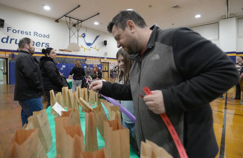 Forest Road 3rd grader Belle Dabkey and her dad Greg pick out auction items while attending the St. Baldrick fundraiser held Thursday, March 7, 2024.