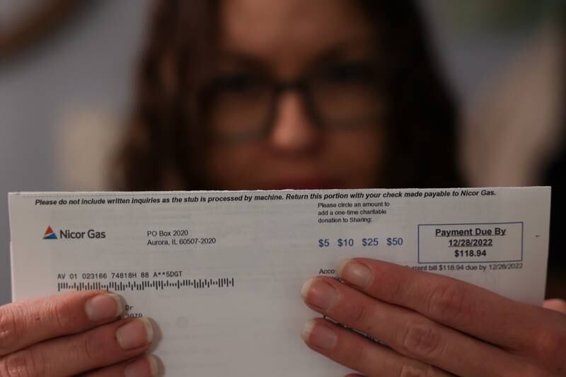 Kara Anderson holds her recent gas bill for $118, nearly four time her average bill.