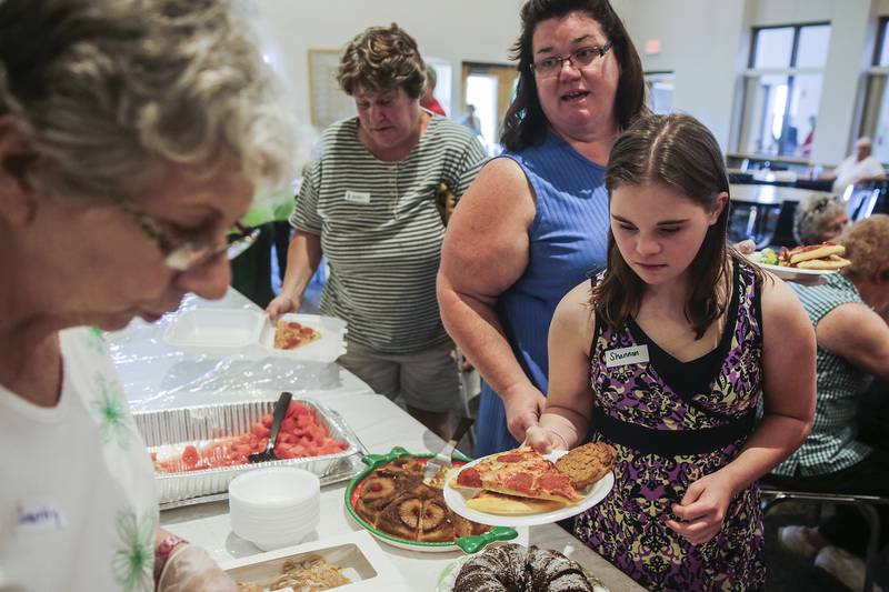 Kristin and Shannon Wexell, 13, receive food from the disaster relief center at Coal City United Methodist Church, Wednesday, June 24, in Coal City. Photo by Lathan Goumas - lgoumas@shawmedia.com