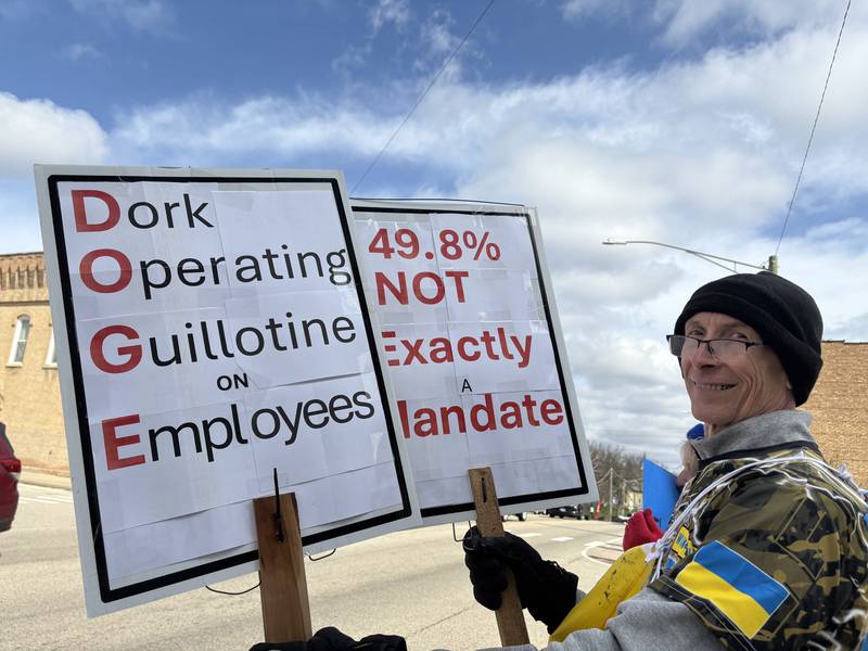 Matt Kovar of Hebron holds up signs opposing President Donald Trump and Elon Musk-led Department of Government Efficiency in Richmond April 19, 2025.