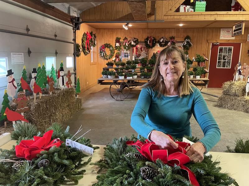 Wendy Richardson adjusts a ribbon on one of the fresh wreaths crafted on-site at the Richardson Christmas Tree Farm.