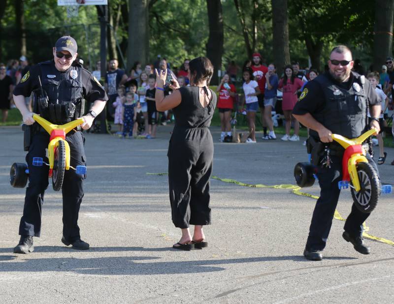Spring Valley Police officers Zane Behrens and Josh Pellegrini compete in the adult petal car race during the National Night Out on Tuesday, Aug. 2, 2022 at Kirby Park in Spring Valley.