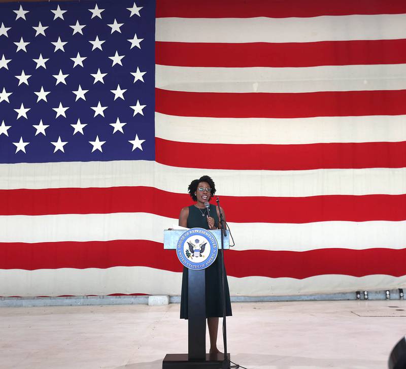 U.S. Rep. Lauren Underwood, D-Naperville, speaks in front of a large American Flag Tuesday, Aug. 23, 2022, during a town hall meeting in one of the hangers at the DeKalb Taylor Municipal Airport.