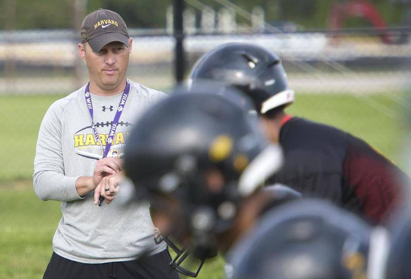 Harvard coach Sean Saylor starts the timer on his watch Monday, Aug. 7, 2017, as his plays start a shuttle run. The players had to complete six down-and-backs under a certain time depending on their position group.