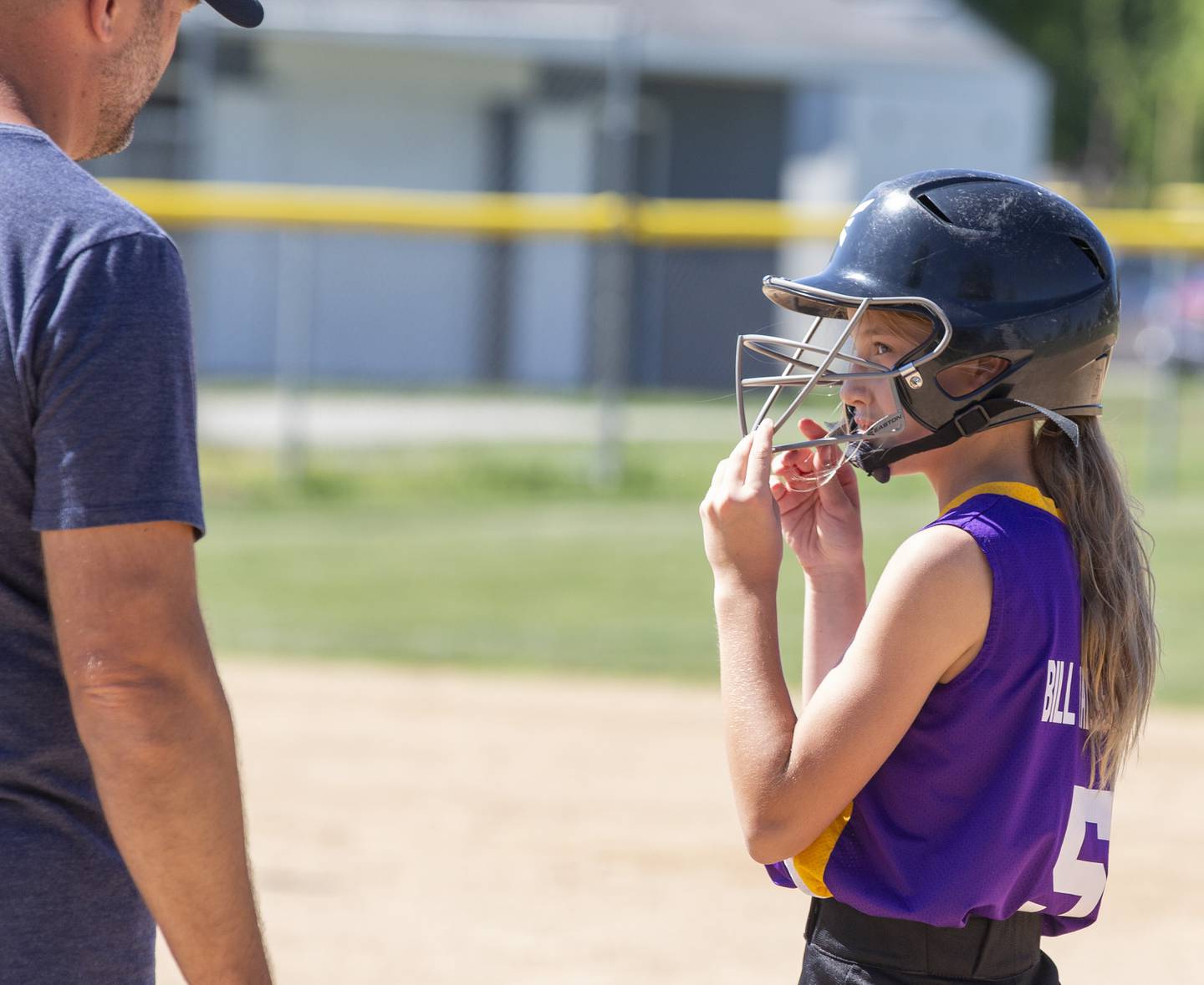 The Warriors' Harper Carlson (5) talks with her first-base coach in the third inning Saturday, July 9, 2022, during the Ottawa Girls Fastpitch Association 11U city championship game at Peck Park.