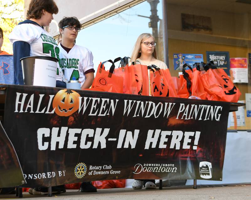 Participants get their supplies during the Halloween Window painting event held in Downtown Downers Grove on Saturday Oct. 21, 2023.
