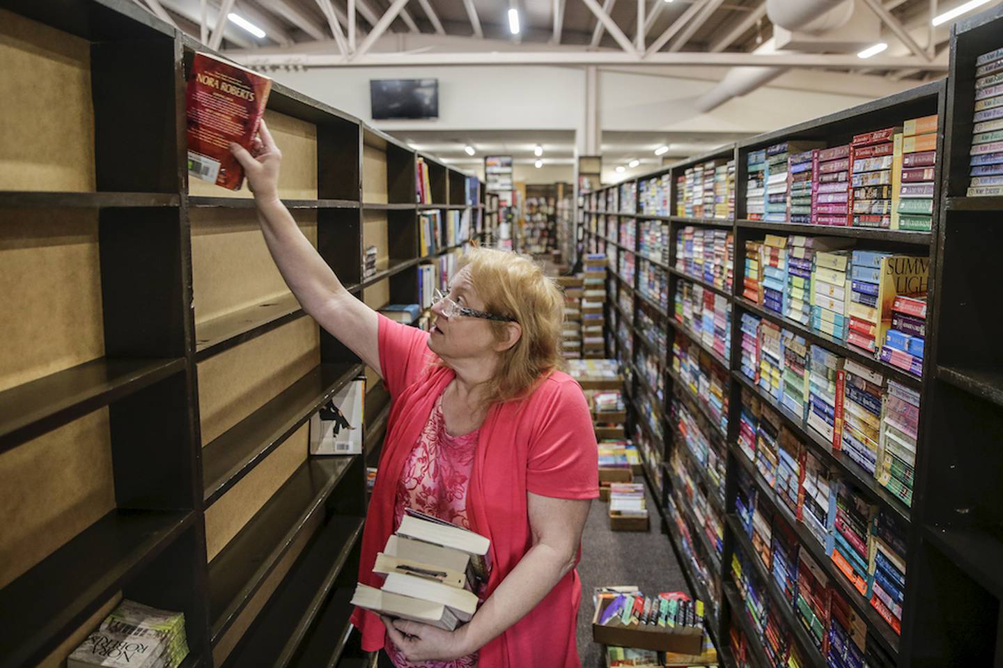 Jan Staley places books on a shelf April 3 as she organizes the new location of The Book Market in Crest Hill. After 38-years of renting retail space Stanley now owns her location.