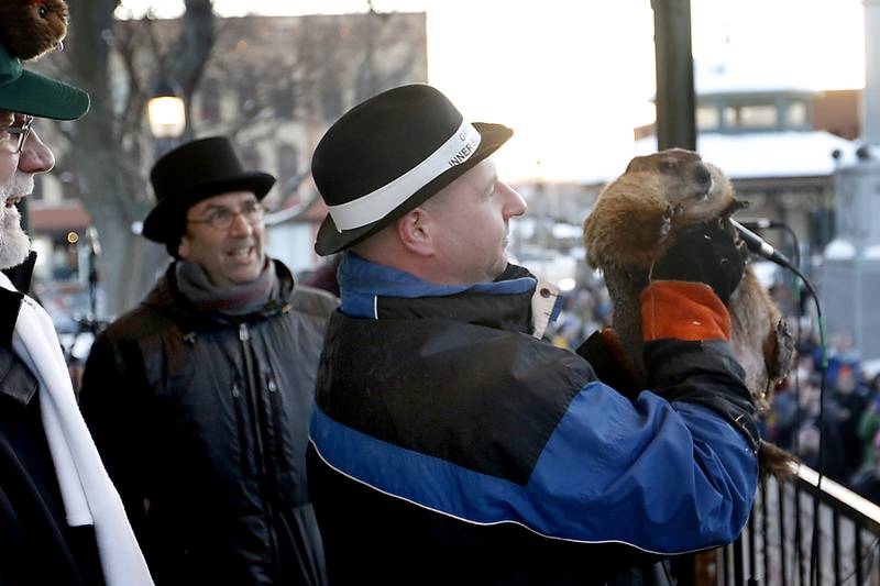 Woodstock Willie is held by handler Mark Szafran as Willie looks to see if he can see his shadow Thursday, Feb. 2, 2023, during the annual Groundhog Day Prognostication on the Woodstock Square.