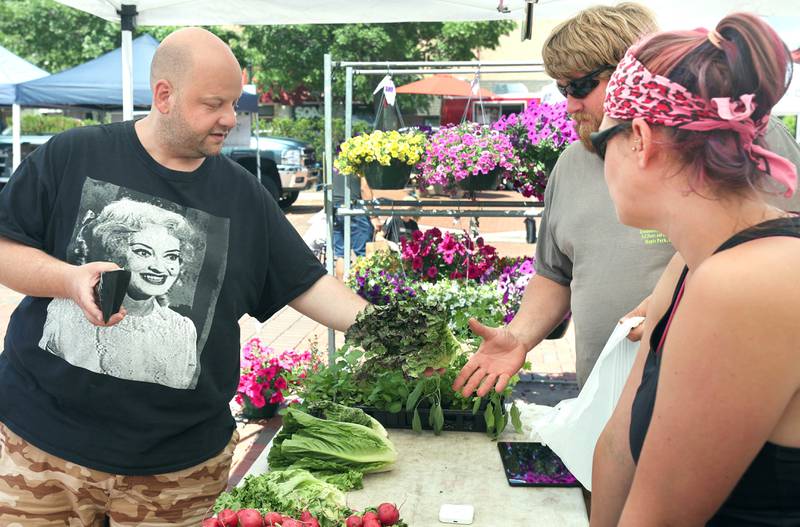 Kris Waramoski, (left) from Channahon, makes a purchase at the Theis Farm Market booth Thursday, June 2, 2022, during the first DeKalb Farmers Market of the season at Van Buer Plaza in Downtown DeKalb.