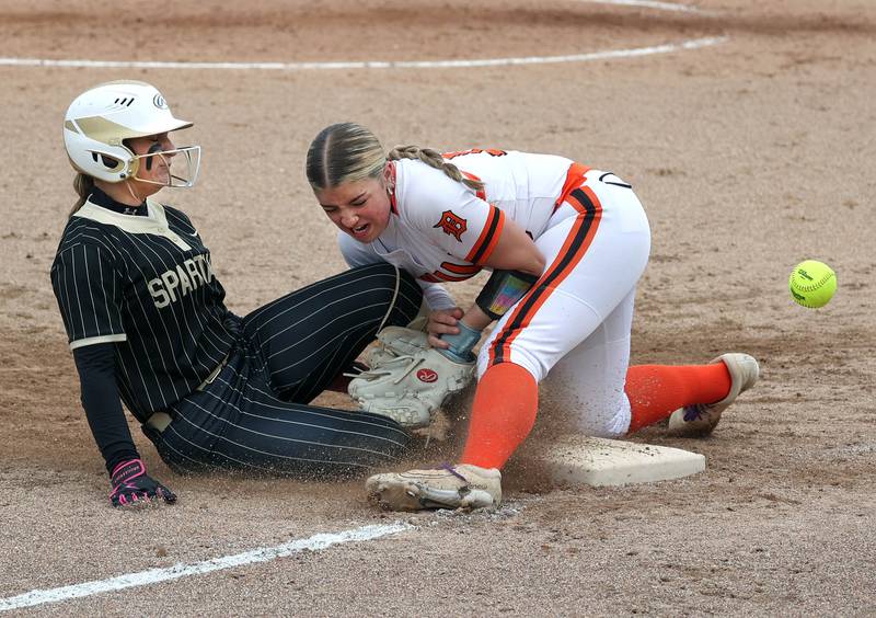 Sycamore's Annabella Johnson slides safely into third but accidentally spikes DeKalb's Kennedy Latimer in the knee Friday, May 2, 2025, during their game at DeKalb High School. Latimer was injured on the play.