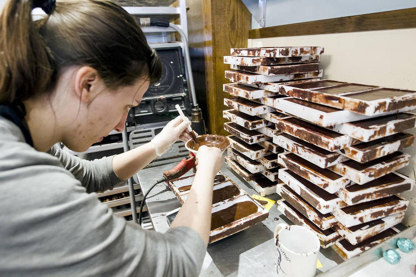 Chocolatier Hannah Marsili adds chocolate to molds while making chocolate bars at Ethereal Confections in Woodstock.