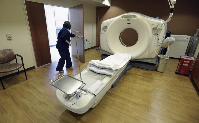 FILE - In this Jan. 9, 2013, file photo, a CT scan technician prepares for a patient at the Silver Cross Emergency Care Center in Homer Glen, Ill. A team of doctors at the Henry Ford Health System in Michigan used back-to-back CT scans and MRIs to make the diagnosis of acute necrotizing encephalitis (ANE) in a 58-year-old female patient who tested positive for coronavirus. (AP Photo/M. Spencer Green, File)