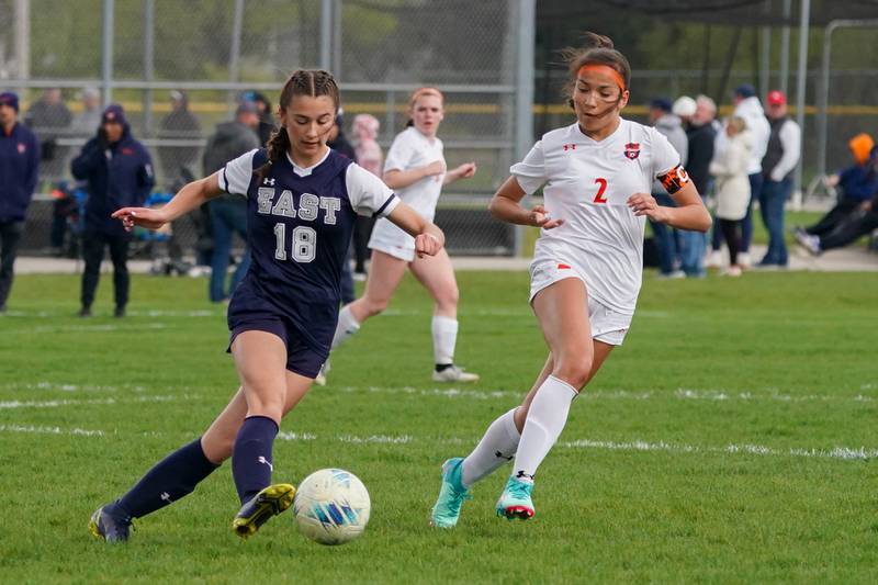 Oswego East's Ashley Gumm (18) plays the ball above the box against Oswego’s Grace Braun (2) during a soccer match at Oswego East High School on Tuesday, April 23, 2024.
