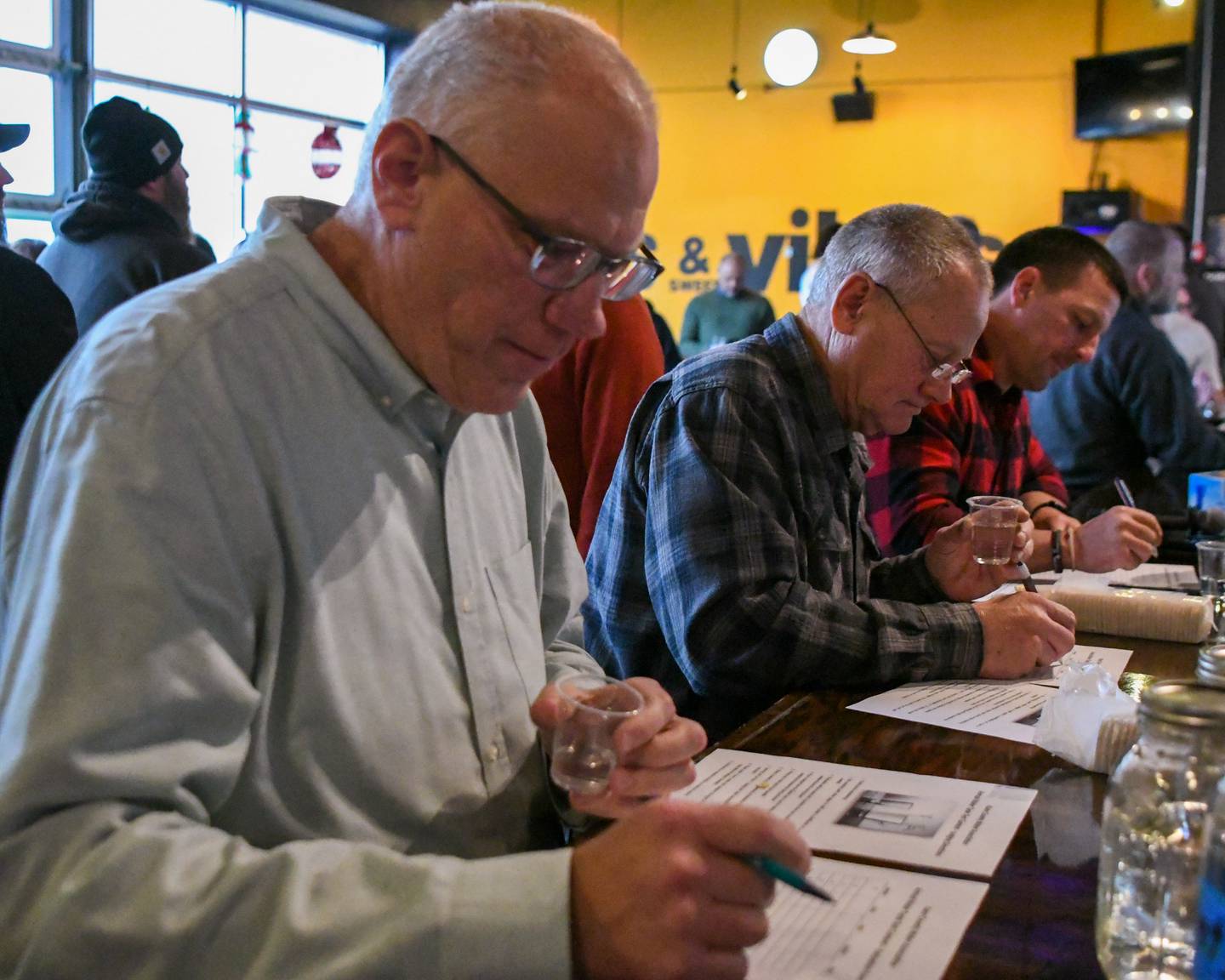 Gary Holm, Dan Mann and Zach Jardine taste test nine different city’s water along with other criteria to determine who has the best water in Kane County on Thursday Dec. 18, 2025, during the Kane County Water Association water contest held at Global Brew Tap House in St. Charles.