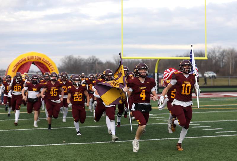 Richmond-Burton's Ray Hannemann and Luke Robinson lead the Rockets onto the field for their IHSA Class 3A semifinal playoff football game against Byron on Saturday, November 22, 2025, at Richmond-Burton High School, in Richmond.