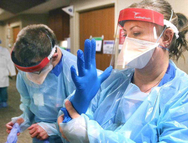 March 22, 2021 File photo - Nurse Shawn Petritsch and charge nurse Angie Bogle put on gloves as part of their personal protective equipment Friday in the Intermediate Care Unit at Northwestern Medicine Kishwaukee Hospital in DeKalb.