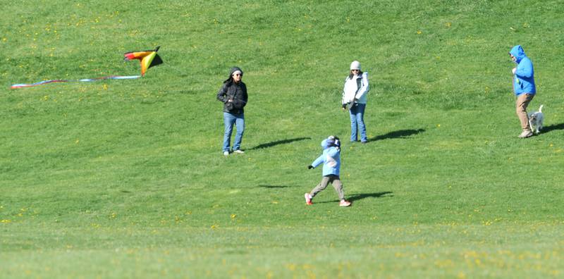 A family watches as an youngster runs with his kite during a celebration of Earth Day and National Kite Month at Prairie Point Park in Oswego, Saturday, April 20, 2024.
