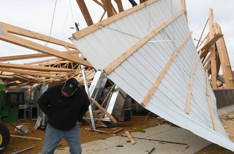 Jim Ludwig of Lanark ducks under one of the beams of his large machine shed after it was leveled during Friday's storm along Illinois 64 about 5 miles east of Lanark.