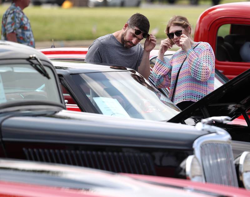 Patrick Meisch, from Cortland, and Samantha Crump, from Bloomington, take off their glasses to get a better look at one of the vehicles Saturday, June 14, 2025, at the Flag Day Car Show in the Hy-Vee parking lot in Sycamore.