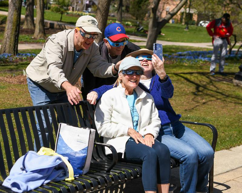 Carmela Martino of Naperville takes a selfie picture of her friends Jan and Michael Moran of Wheaton and her husband John Martino, back left, as they wear the solar eclipse glasses on Monday April 8, 2024, before the start of the eclipse during the watch party outside the Wheaton library.
