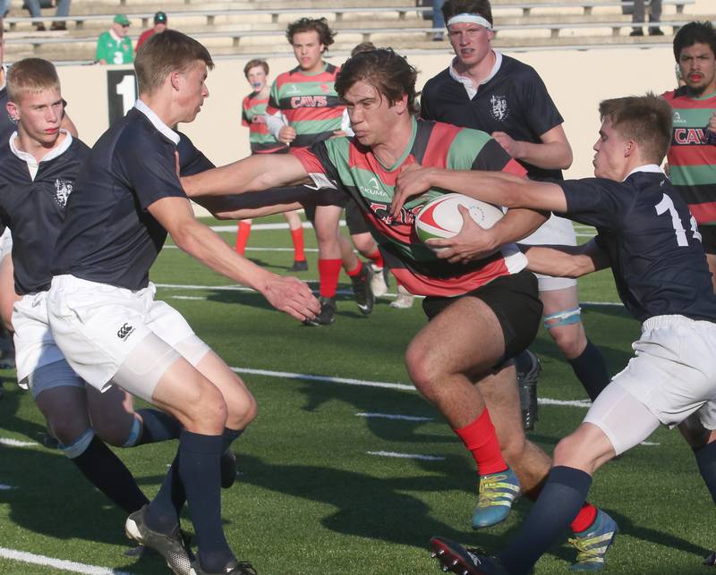 La Salle-Peru's Wyatt Herrman (center) stiff arms La Salette's Eric Nippert while his teammate Henry Kleronomos tries to set the ball free during a rugby game on Wednesday, April 12, 2023 at Howard Fellows Stadium at L-P High School.