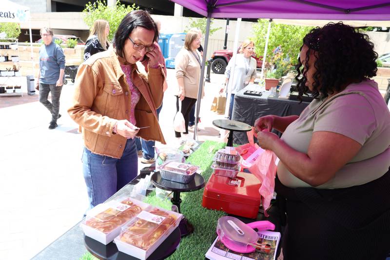 Lynn McGann buys cake at one of the tents at the new city square for the farmers market on Friday, May 22, 2026 in Joliet.