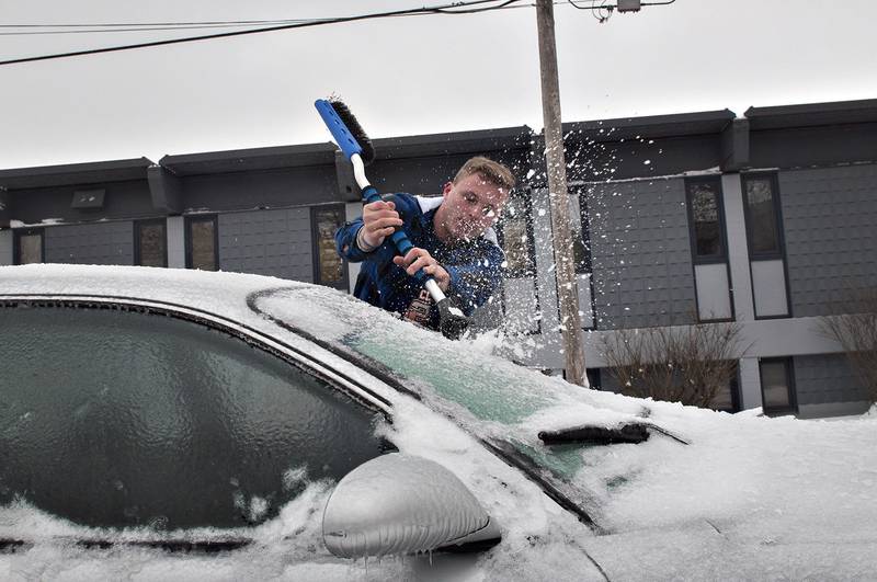 Kade Frey chips through ice on a car in Dixon. Vehicles, trees and any outside structure received a coating of ice from the recent freezing rains.
