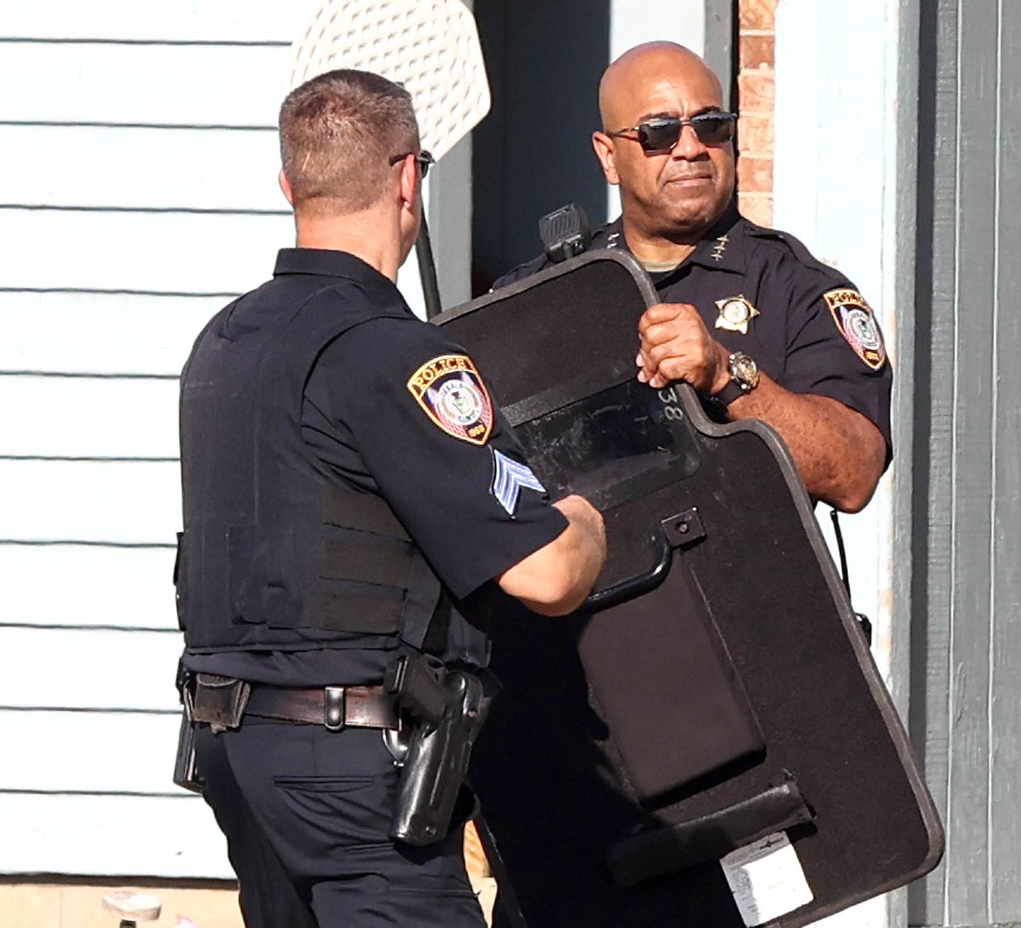 DeKalb Police Chief David Byrd (right) hands a shield back to an officer at the scene of a shooting Wednesday, Aug. 24, 2022, at West Ridge Apartments in DeKalb.