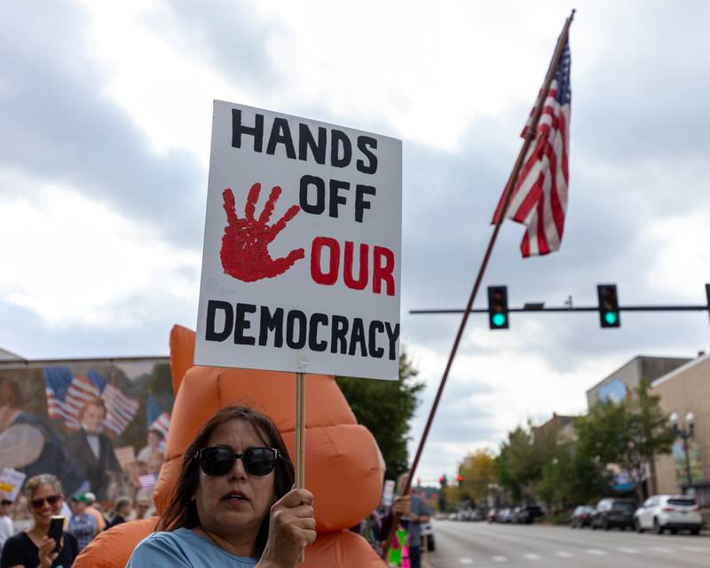 Protester holds sign above head at the ‘No Kings 2.0’ Protest on Saturday, October 18, 2025 at Washington Square Park in Ottawa.