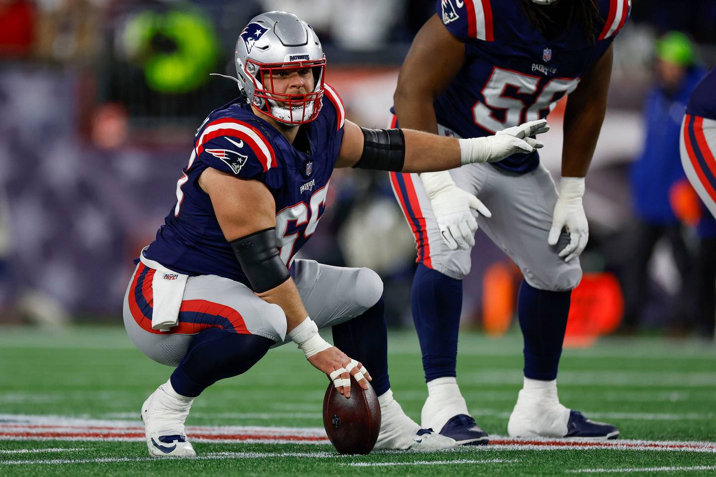 New England Patriots center Garrett Bradbury (65) makes a call at the line of scimmage during the first half of an NFL wild card playoff football game against the Los Angeles Chargers, Sunday, Jan. 11, 2026, in Foxborough, Mass. (AP Photo/Greg M. Cooper)