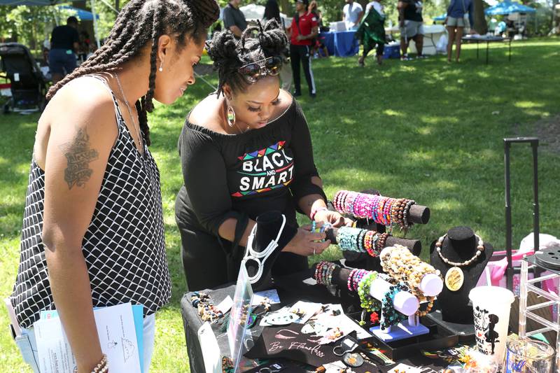 Diamond Ellis (right) helps Deborah Bradley, from Cortland, pick out a bracelet for her daughter at one of the booths during the second annual Juneteenth celebration Sunday, June 19, 2022, at Hopkins Park in DeKalb.