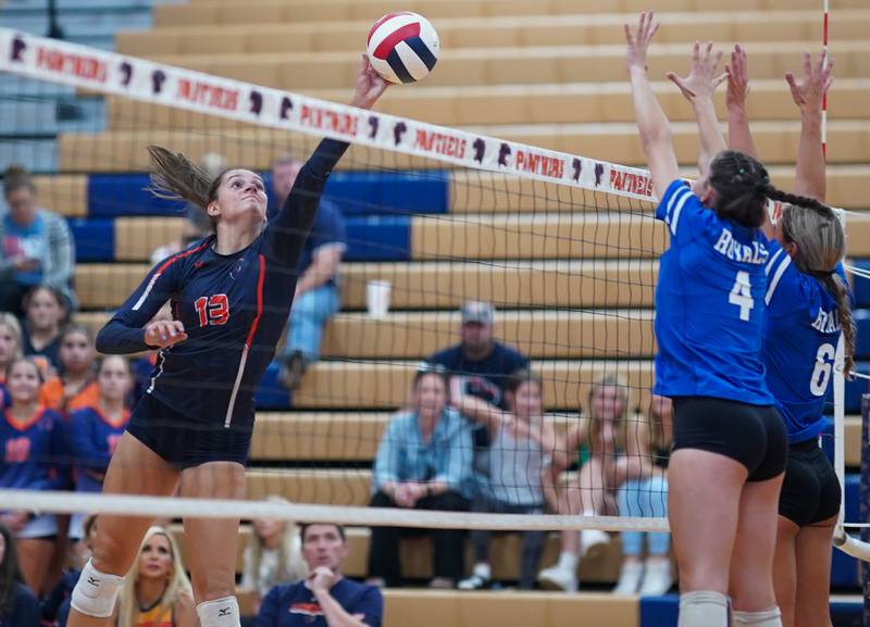 Oswego’s Sidney Hamaker (13) goes up for a kill against Rosary’s Reese Gilla (4) and Lily Caruso (6) during a volleyball match at Oswego High School on Tuesday, Aug 29, 2023.