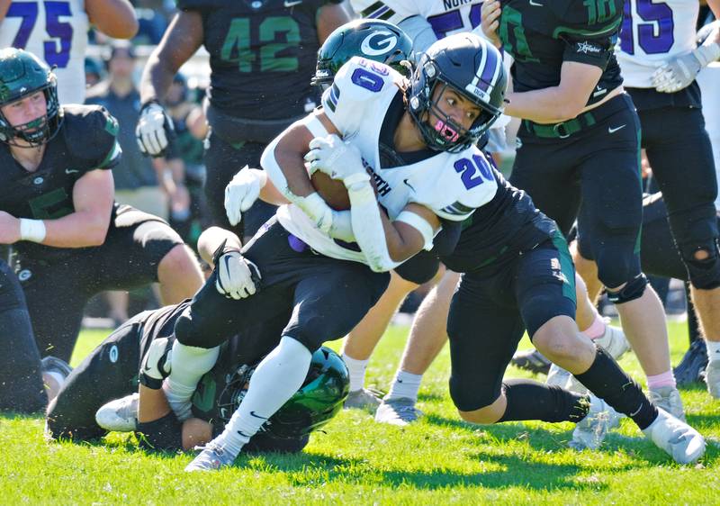 Downers Grove North running back Noah Battle (20) lunges for more yardage as he is in the grasp of the Glenbard West defense during a game on Oct. 8, 2022 at Glenbard West High School in Glen Ellyn.