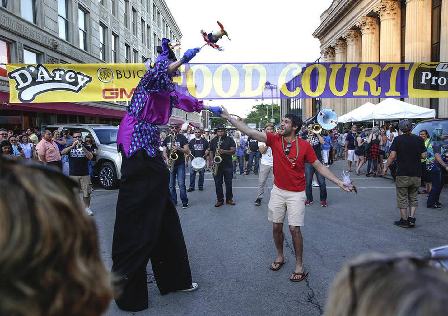 An audience member dances with a stilt walker Friday during the New Orleans North celebration in downtown Joliet.