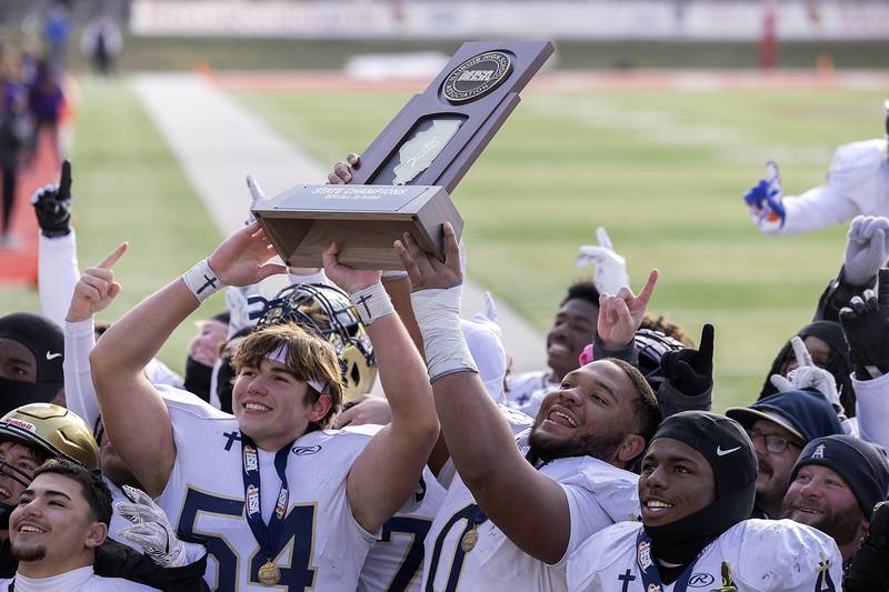 Althoff Catholic’s Patton Leib (left) and Jason Dowell raises the trophy after their  52-14 win over Lena-Winslow Friday, Nov. 29, 2024, in the class 1A football state final.