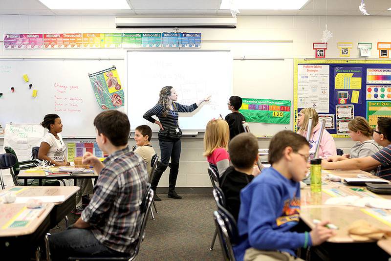 Fifth-grade teacher Heather Engelhart helps fifth-grader Jose Tellez with a math problem on her classroom's Smart Board at Harrison Street Elementary School in Geneva. The board was donated to the school.
