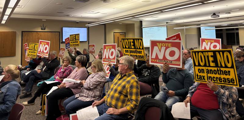 Attendees hold up vote no signs at the McHenry County Board budget and levy vote Nov. 19. 2024.
