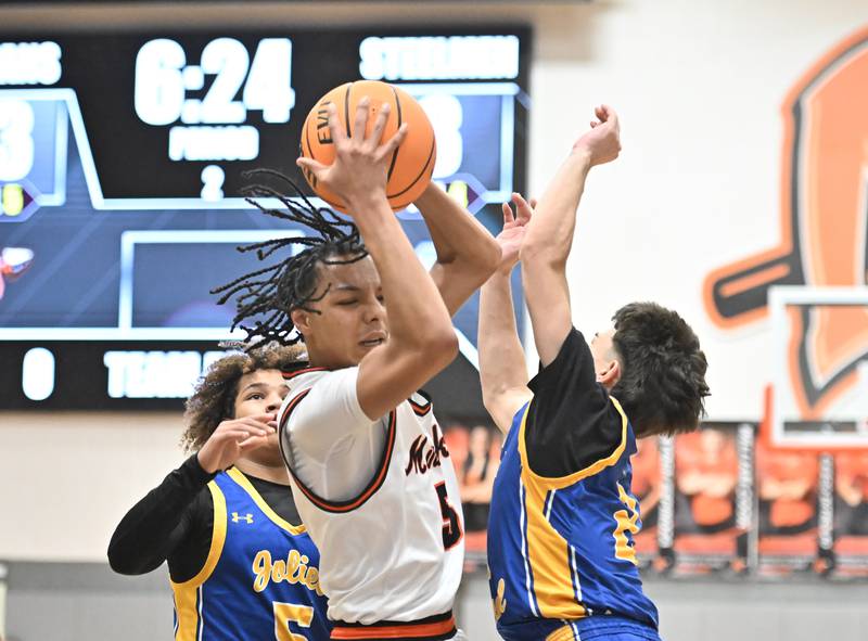 Minooka's Jordan Freeman (5) tries to get out of a double team during a conference game against Joliet Central on Friday, Jan. 10, 2025, at Minooka.