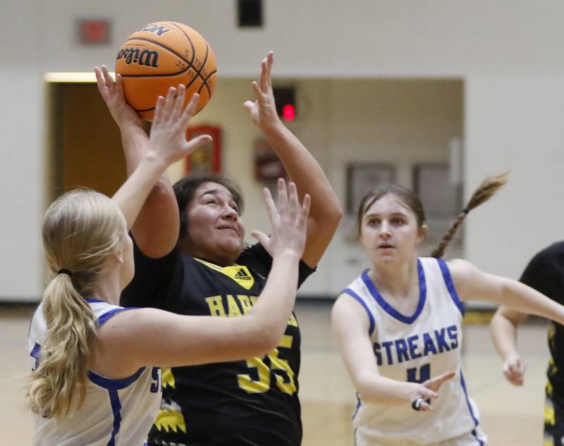 Harvard's Crystal Gonzalez tries to shoot the ball between \w31(left) and Emma Douglas (right) during a Kishwaukee River Conference girls basketball game on Monday Jan. 12, 2026, at Woodstock High School.