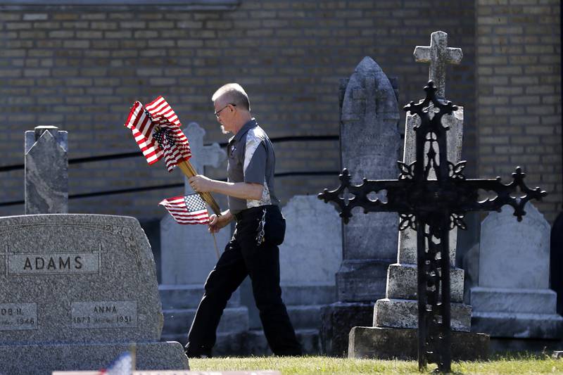 U.S. Army veteran Alex Januk searches for veterans graves as volunteers help former members of Johnsburg VFW Post 11496, which recently merged with Lake Villa VFW Post 4308, place flags Friday, May 26, 2023, at the graves of over 150 veterans at St. John the Baptist Cemetery, in Johnsburg.