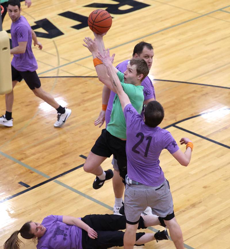 Fire/Police team member Ryan Gustafson goes between two Sycamore School Staff team players Thursday, Dec. 19, 2024, during the Heroes on Hardwood basketball game at Sycamore High School. The basketball game, which is a fundraiser for the Spartan Food Pantry, pits a team of Sycamore first responders against a squad of Sycamore School District 427 staff.