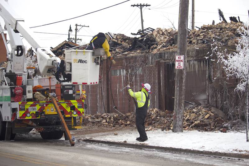 Two workers at the scene of the destroyed remains of a commercial building seen on Friday, Jan. 30, 2026, near South Eastern Avenue and Washington Street in Joliet. The building was demolished following a fire on Thursday, Jan. 29, 2026.